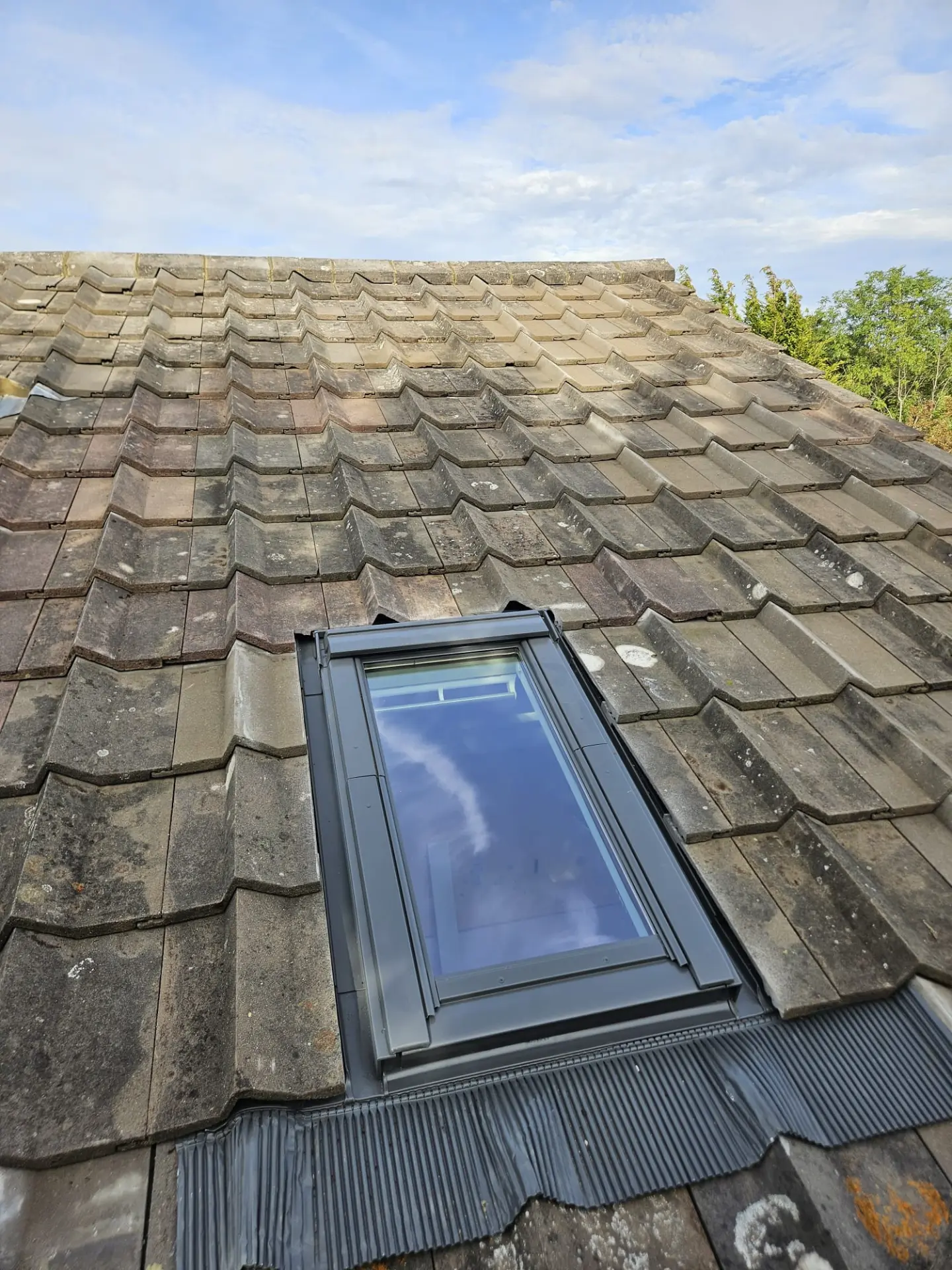 Interlocking concrete tiled roof with a new roof window and flashing in Surrey