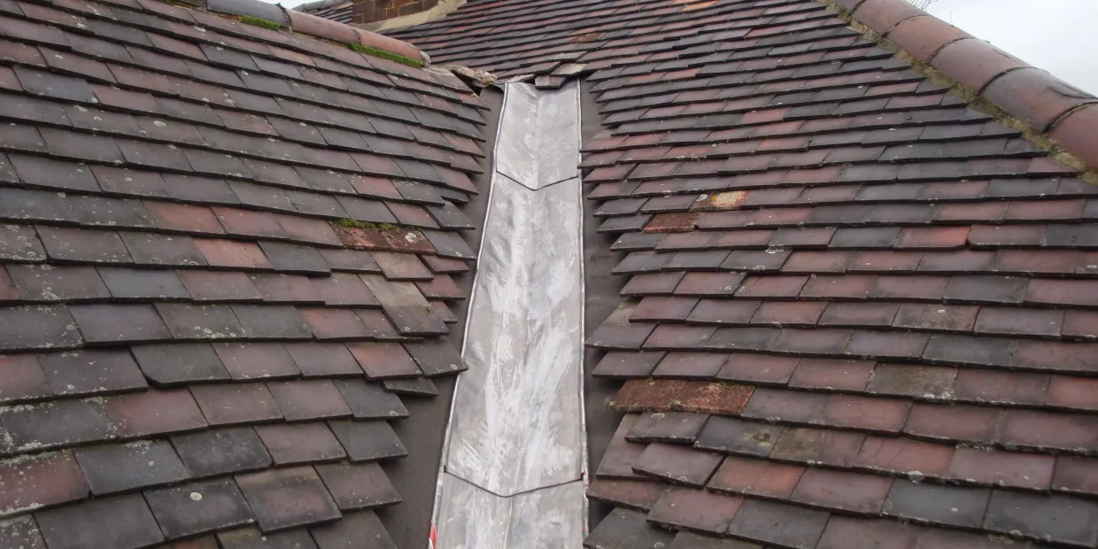 New lead valley laid between plain clay tiled roof slopes in Surrey